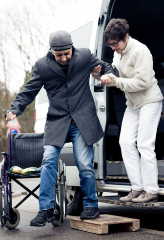 old lady helping her husband to walk out from the van